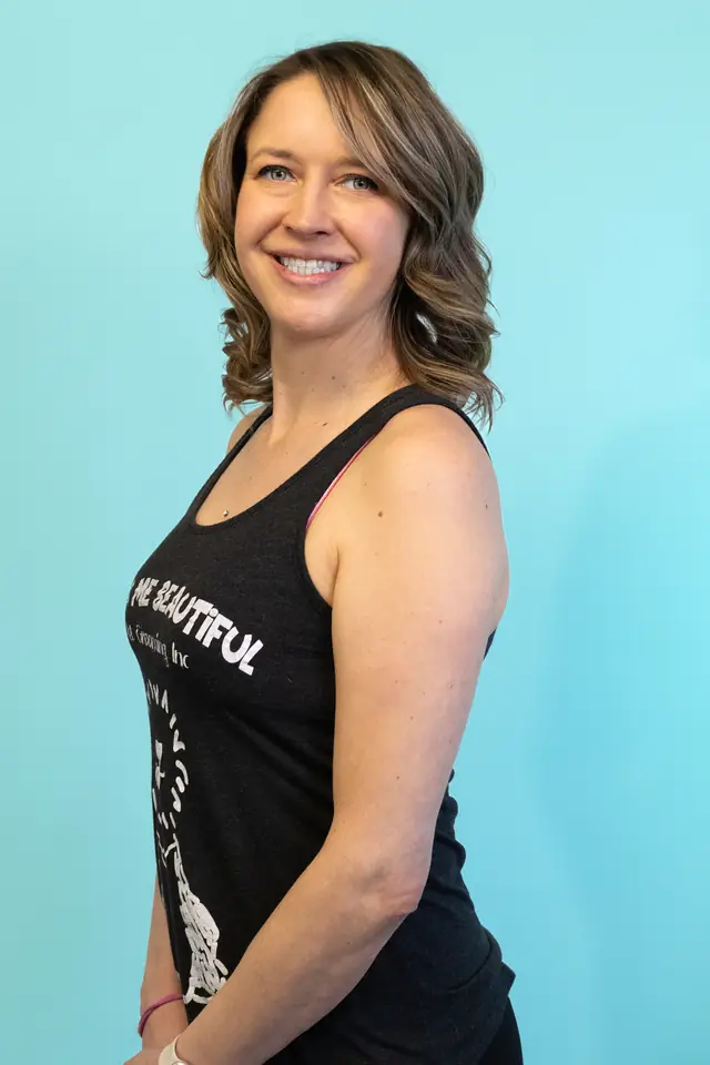 A team member in a black Bark Me Beautiful tank top against the turquoise wall